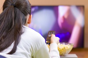 Relaxed teenage girl with remote control watching smart TV